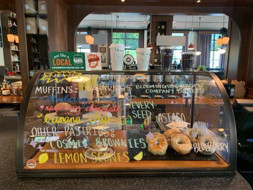 Display case with colorful chalkboard menu featuring muffins, pastries, bagels, and other baked goods.