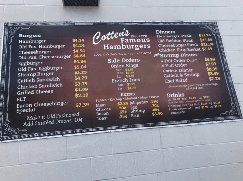 Menu board for Cotten's Famous Hamburgers featuring burgers, dinners, sides, extras, and drinks with prices listed.