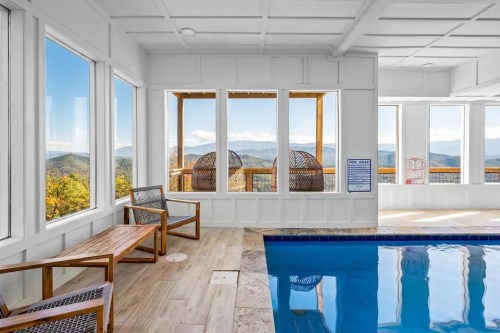 Indoor pool area with wooden seating and large windows showcasing mountain views. Bright and airy atmosphere.
