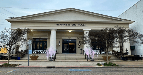 A classic building with columns, labeled "Frankie's on Main," featuring outdoor seating and decorative trees.