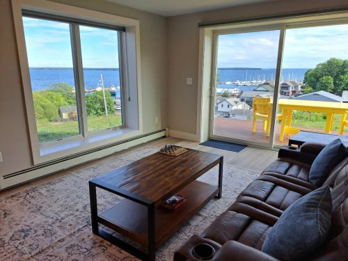 Cozy living room with a view of the water, featuring a chessboard on a wooden table and large windows.