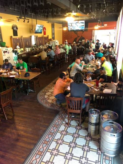 A busy restaurant interior with patrons dining at tables and a bar, featuring a lively atmosphere and decor.