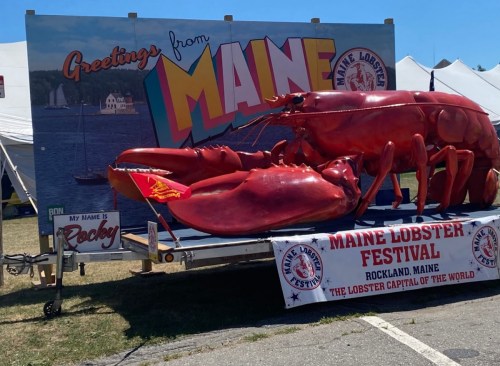 A large lobster statue with a sign reading "Greetings from Maine" at the Maine Lobster Festival in Rockland, Maine.