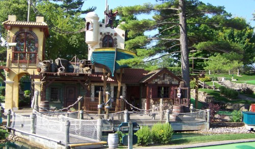 A whimsical pirate-themed building with a boat, surrounded by greenery and decorative elements.