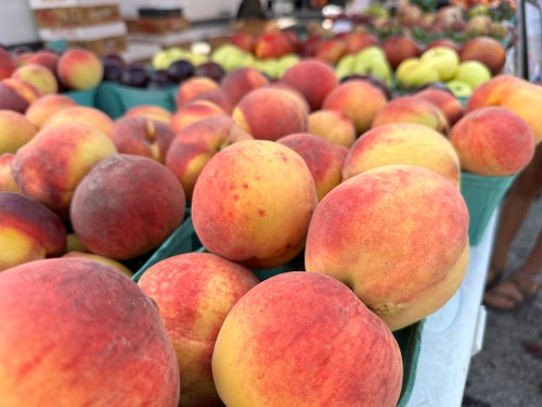 A close-up of fresh, ripe peaches displayed in green baskets at a market.