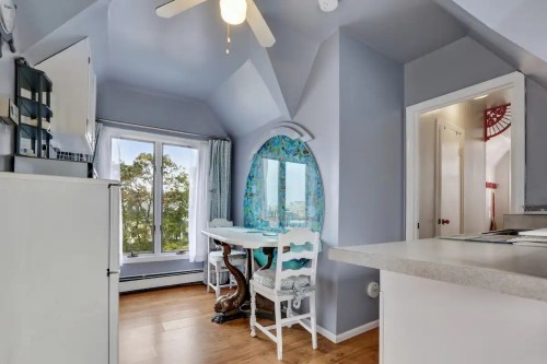 Cozy kitchen nook with a table and chairs, large windows, and light blue walls in a bright, airy space.