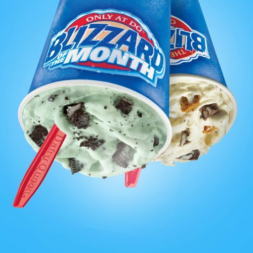 Two Dairy Queen Blizzard cups, one mint with Oreo pieces and the other with chocolate and caramel, against a blue background.