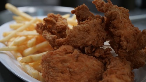 A plate of crispy fried chicken pieces served with golden French fries.