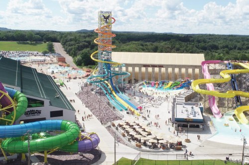 Aerial view of a water park featuring colorful slides, pools, and a large crowd enjoying the attractions on a sunny day.