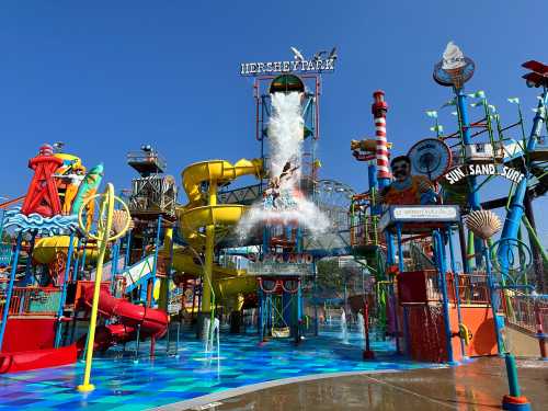 A vibrant water park with colorful slides, a large splash area, and bright blue skies in the background.