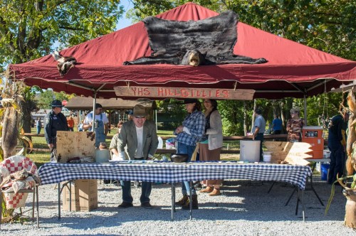 A tent with a sign reading "YHS Hillbillies" features people selling goods at an outdoor market.