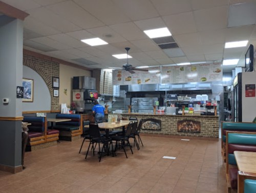 A casual dining area with tables and chairs, featuring a counter and menu board in a cozy restaurant setting.
