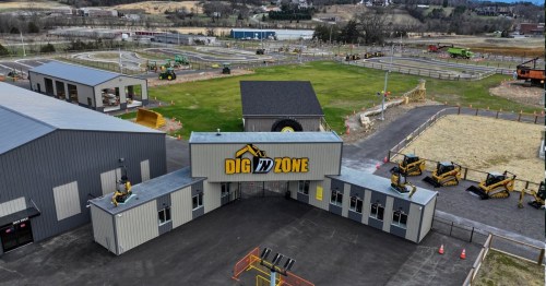 Aerial view of Dig Zone, featuring construction equipment, tracks, and a grassy area with buildings in the background.