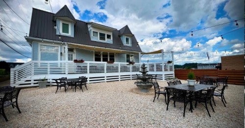 A charming house with a patio area, surrounded by gravel and outdoor seating, under a cloudy sky with string lights.