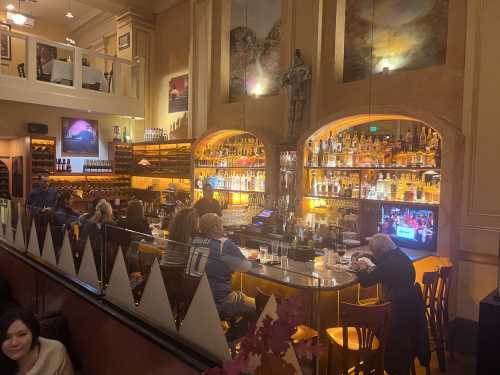 A cozy bar scene with patrons enjoying drinks, illuminated shelves of bottles, and warm lighting.