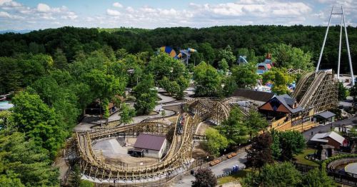 Aerial view of a theme park featuring a wooden roller coaster surrounded by trees and various attractions.