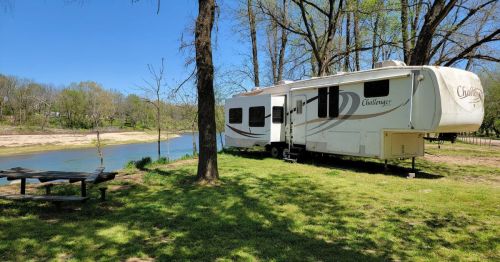 An RV camper parked up along the shores of the Illinois River at a campground in Oklahoma