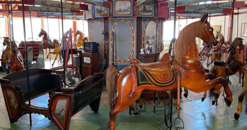 A vintage carousel featuring intricately painted wooden horses and a decorative chariot in a nostalgic setting.