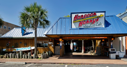 Exterior of Harpoon Harry's Waterfront Cafe, featuring a blue roof, wooden structure, and palm trees.