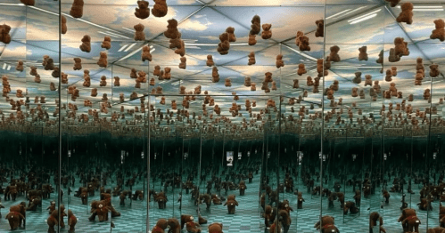 A mirrored room filled with teddy bears hanging from the ceiling, creating a surreal, infinite reflection effect.