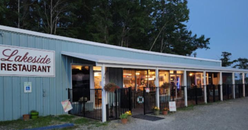Lakeside Restaurant exterior at dusk, featuring a blue building with outdoor seating and surrounding trees.