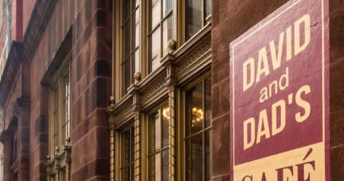 Sign for "David and Dad's Café" on a building with large windows and ornate architectural details.