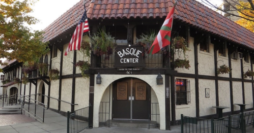 Exterior of the Basque Center, featuring a distinctive building with flags and decorative plants.