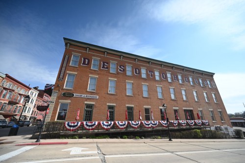 Historic DeSoto House Hotel with patriotic bunting, set against a clear blue sky.