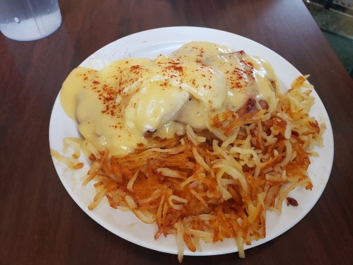 A plate of crispy hash browns topped with creamy sauce and garnished with paprika.