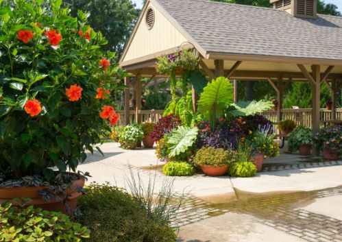 A vibrant garden with colorful flowers and lush greenery surrounding a wooden gazebo.