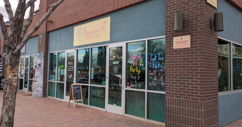 Exterior of a tea shop with colorful signage, large windows, and a chalkboard menu outside.