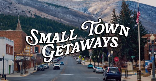 A scenic small town street with mountains in the background, featuring shops and a stop sign. Text overlay: "Small Town Getaways."