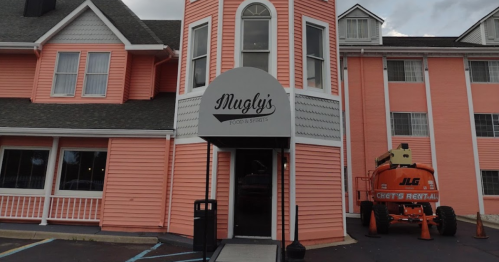 Exterior of Magly's Food & Spirits, a pink building with a round entrance and construction equipment nearby.