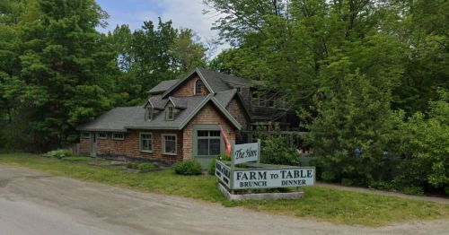 A rustic building surrounded by trees, featuring a sign that reads "Farm to Table Brunch Dinner."