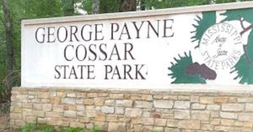 Sign for George Payne Cossar State Park in Mississippi, featuring stone base and green foliage design.