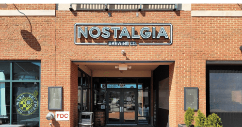 Exterior of Nostalgia Brewing Co. featuring a brick facade and a prominent sign above the entrance.