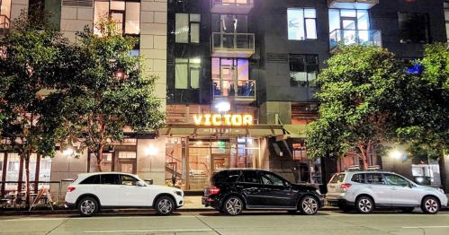 Exterior of Victor Tavern at night, featuring illuminated signage and parked cars along the street.
