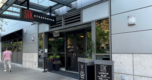 Exterior of STK Steakhouse with a modern entrance and signage, featuring lunch specials displayed outside.