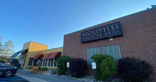 Exterior of Doolittle's Woodfire Grill, featuring a brick facade, large sign, and landscaped entrance.