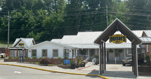 A building with a sign reading "Bush's Best," surrounded by greenery and a parking area.