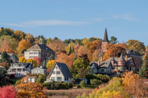 A picturesque town with colorful autumn foliage, featuring charming houses and a steepled church in the background.