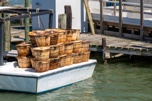 A boat loaded with wooden baskets docked at a pier, surrounded by calm water.