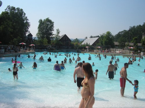 A crowded water park wave pool with people swimming and enjoying the sun on a clear day.