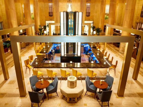 A stylish bar area in a spacious, elegant lobby with modern seating and a striking central feature.