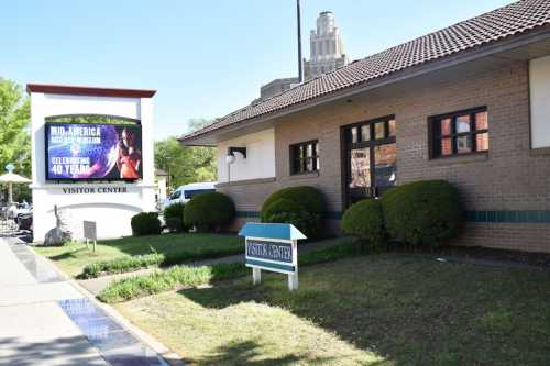 A visitor center building with a sign celebrating 40 years, surrounded by neatly trimmed bushes and a clear blue sky.