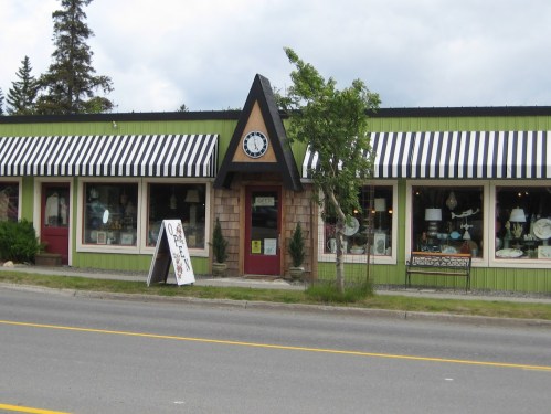 A storefront with a triangular roof, large windows displaying home decor, and a sign that says "Open" in front.