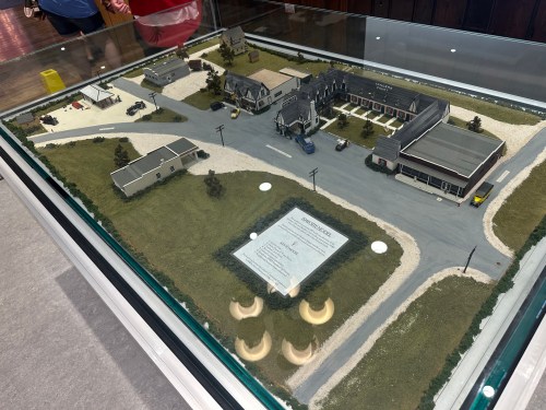 A detailed model of a small town with buildings, roads, and vehicles displayed in a glass case.