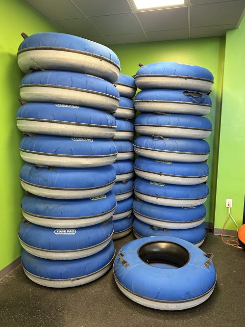 A stack of blue inflatable tubes against a green wall, with one tube lying on the floor in front.