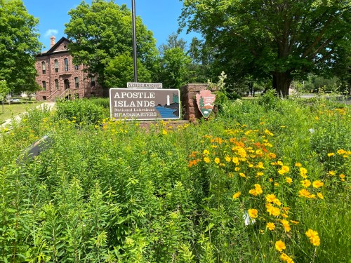A colorful flower garden in front of the Apostle Islands National Lakeshore sign and visitor center.