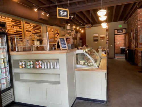 A cozy ice cream shop interior with a service counter, display case, and a staff member behind the counter.